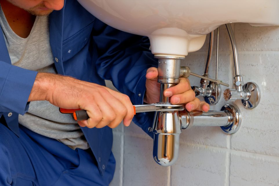a plumber fixes sink pipes