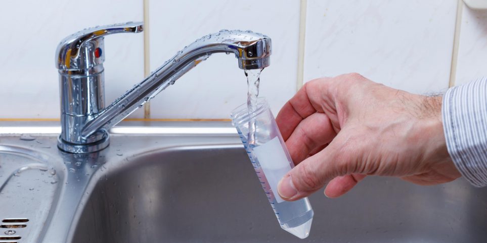 man fills test tube with sink water for testing