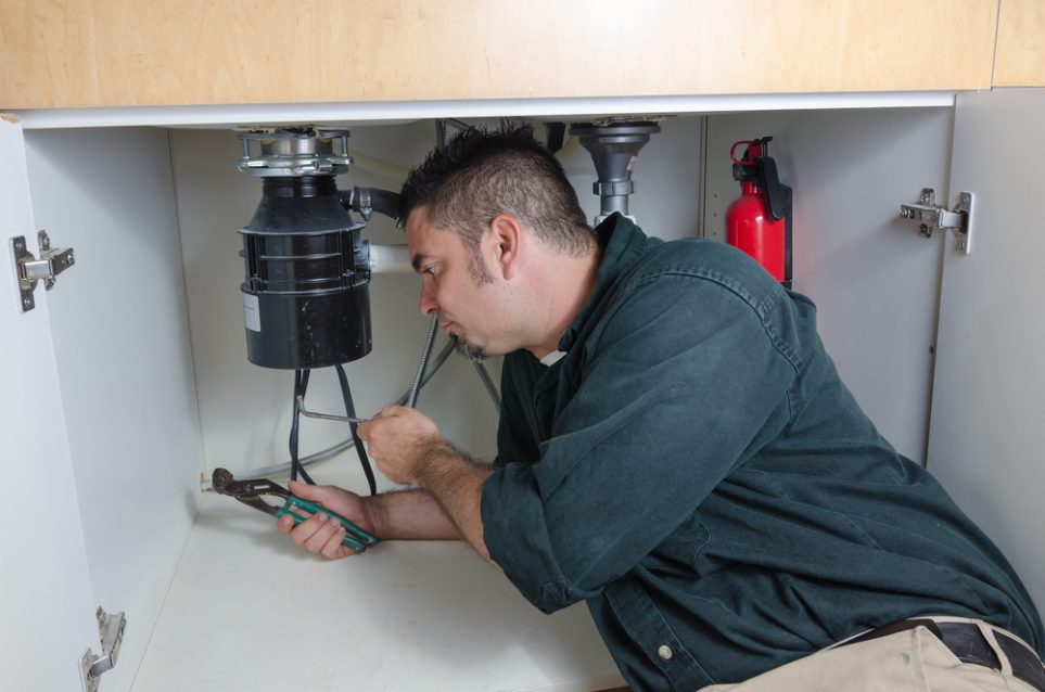 plumber working on garbage disposal repairs.