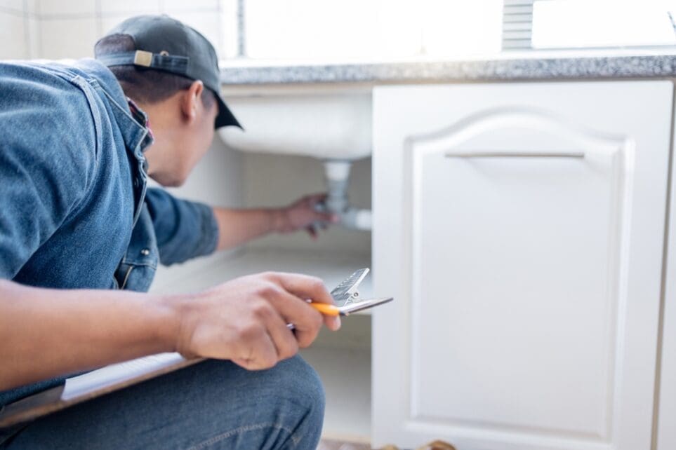 Plumbing by Jake provides commercial water treatment and water softener emergency repair services for homes and businesses across northwest Arizona. This image shows a professional plumbing technician inspecting plumbing connections and water treatment components underneath a sink during an emergency plumbing service call. The setup highlights emergency plumbing support for water filtration systems, water softener repairs, leak detection, and plumbing line issues commonly caused by hard-water conditions in Arizona properties. Plumbing by Jake serves Kingman, Golden Valley, Fort Mohave, Bullhead City, Mohave Valley, and nearby communities with same-day plumbing service and emergency water treatment support.