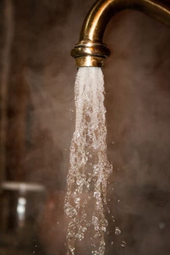 Hot clean water flows from a faucet after a commercial water treatment and softener installation service in Kingman, Arizona. The image highlights improved water clarity, softened water flow, and steam rising from the faucet to represent efficient plumbing and water treatment performance for residential and commercial properties. Plumbing by Jake provides commercial water treatment and softener installation services in Kingman AZ including water filtration systems, reverse osmosis equipment, and hard water solutions designed for Arizona water conditions.